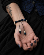 Palm-up view of the Midnight Halo snake bone bracelet showing blue beads, a black sliding knot and dangling vertebrae