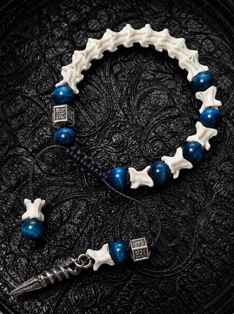 Midnight Relic snake bone bracelet with blue beads, engraved metal spacers and a long pointed pendant on black cords
