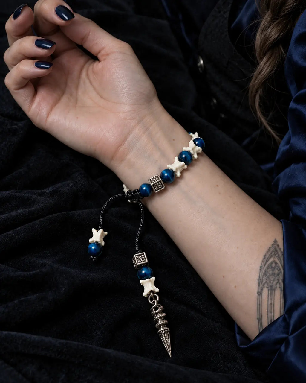 Palm-up view of the Midnight Relic snake bone bracelet showing the sliding knot and long engraved pendant