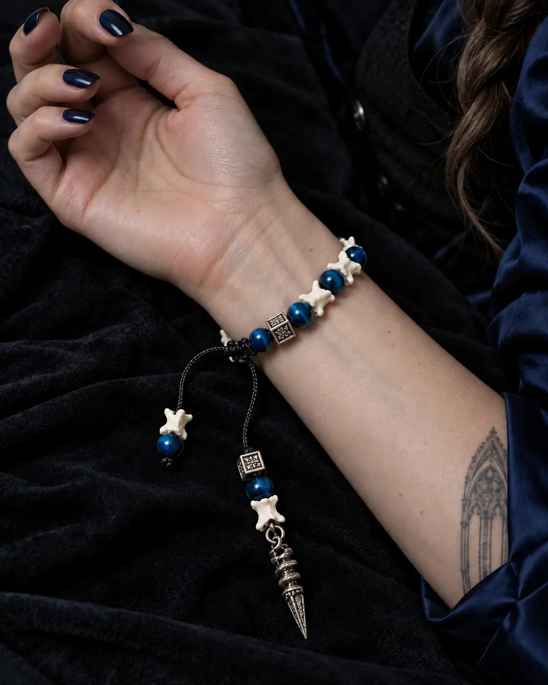 Palm-up view of the Midnight Relic snake bone bracelet showing the sliding knot and long engraved pendant