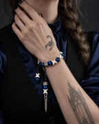 Midnight Relic snake bone bracelet worn with the hand at the neck, showing two dangling bone-and-bead cords