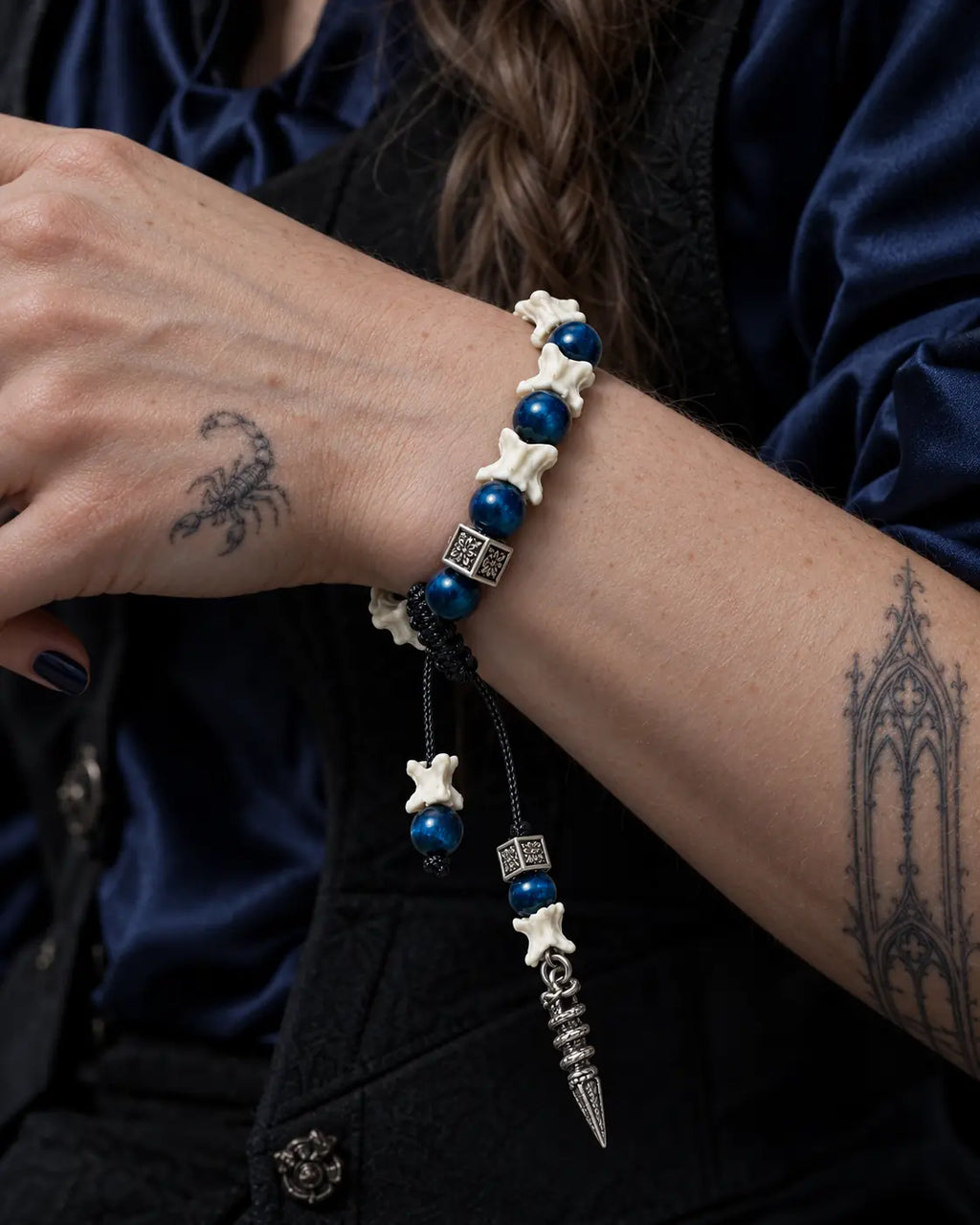 Close-up of the Midnight Relic snake bone bracelet showing blue beads and square metal spacers across the wrist