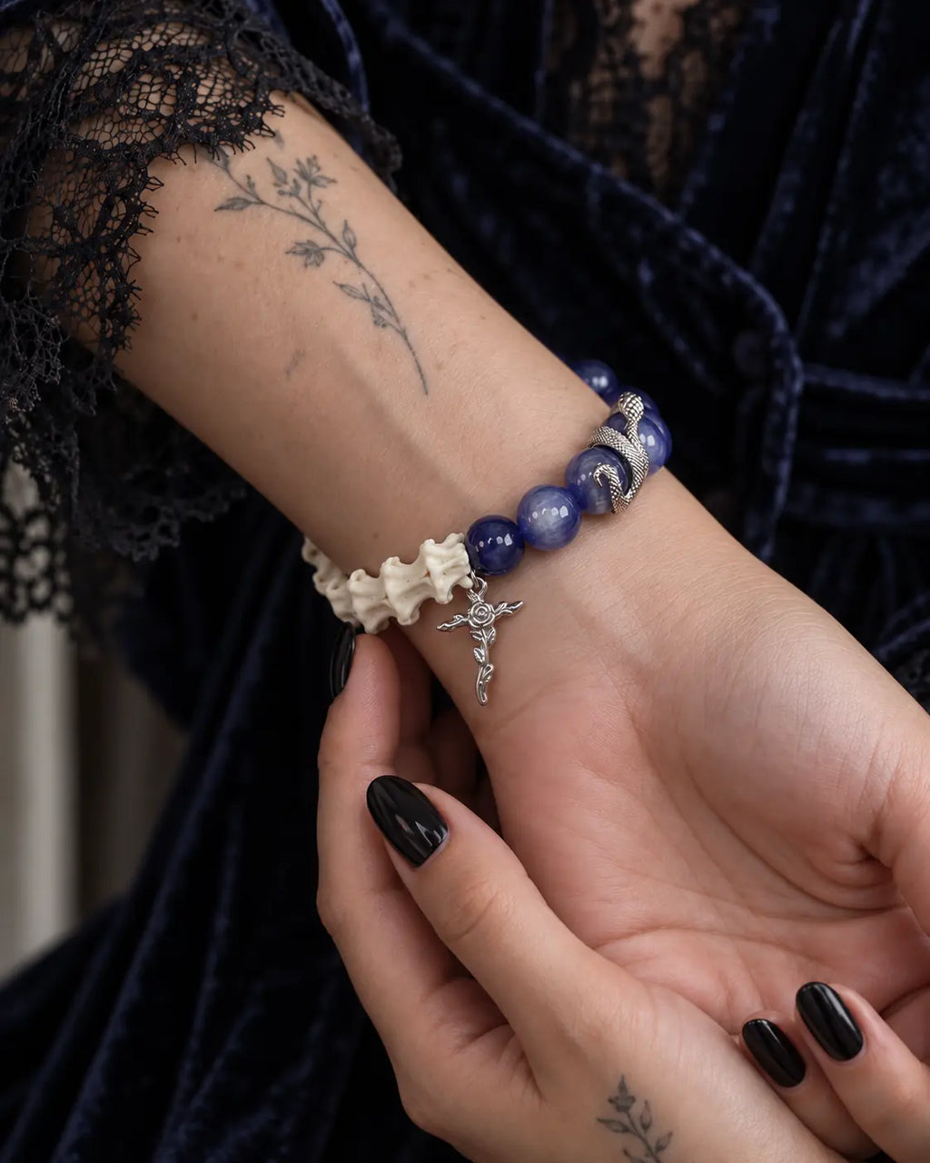Palm-up view of the Midnight Serpent Cross snake bone bracelet with the opposite hand supporting the wrist