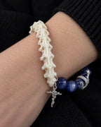 Macro view of the Midnight Serpent Cross snake bone bracelet showing white vertebrae, blue beads and a floral cross