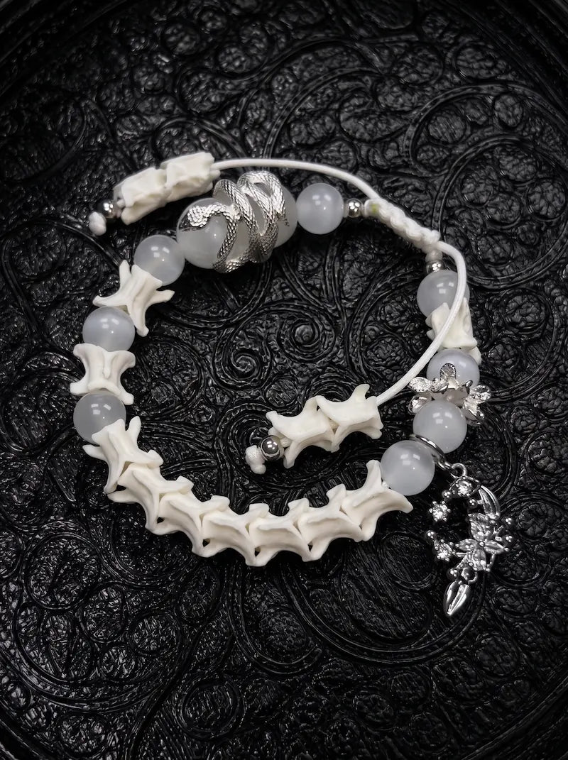 Moon Serpent snake bone bracelet with pale gray beads, a silver-tone serpent, an ornate crescent charm and white cords