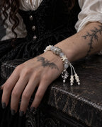 Moon Serpent snake bone bracelet on a wrist resting on a dark stone ledge, showing the crescent and bone-tipped cords