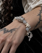 Close-up of the Moon Serpent snake bone bracelet showing a silver-tone serpent, pale gray beads and ornate crescent drop