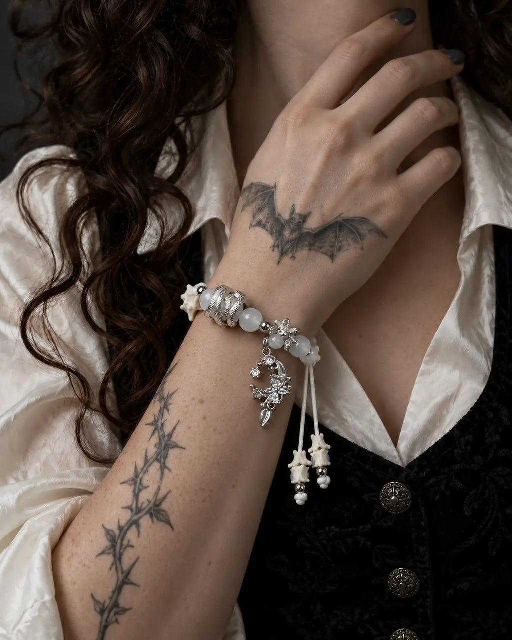 Moon Serpent snake bone bracelet worn with the hand near the neck above a white blouse and black brocade vest