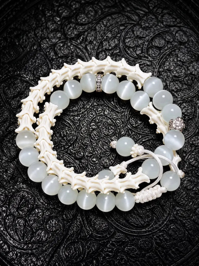 Moonveil double-wrap snake bone bracelet with pale gray beads, white vertebrae and adjustable white cords on black fabric
