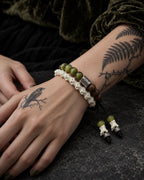 Close-up of the Mosswood snake bone bracelet showing green and brown beads, engraved spacers and dangling bone tips