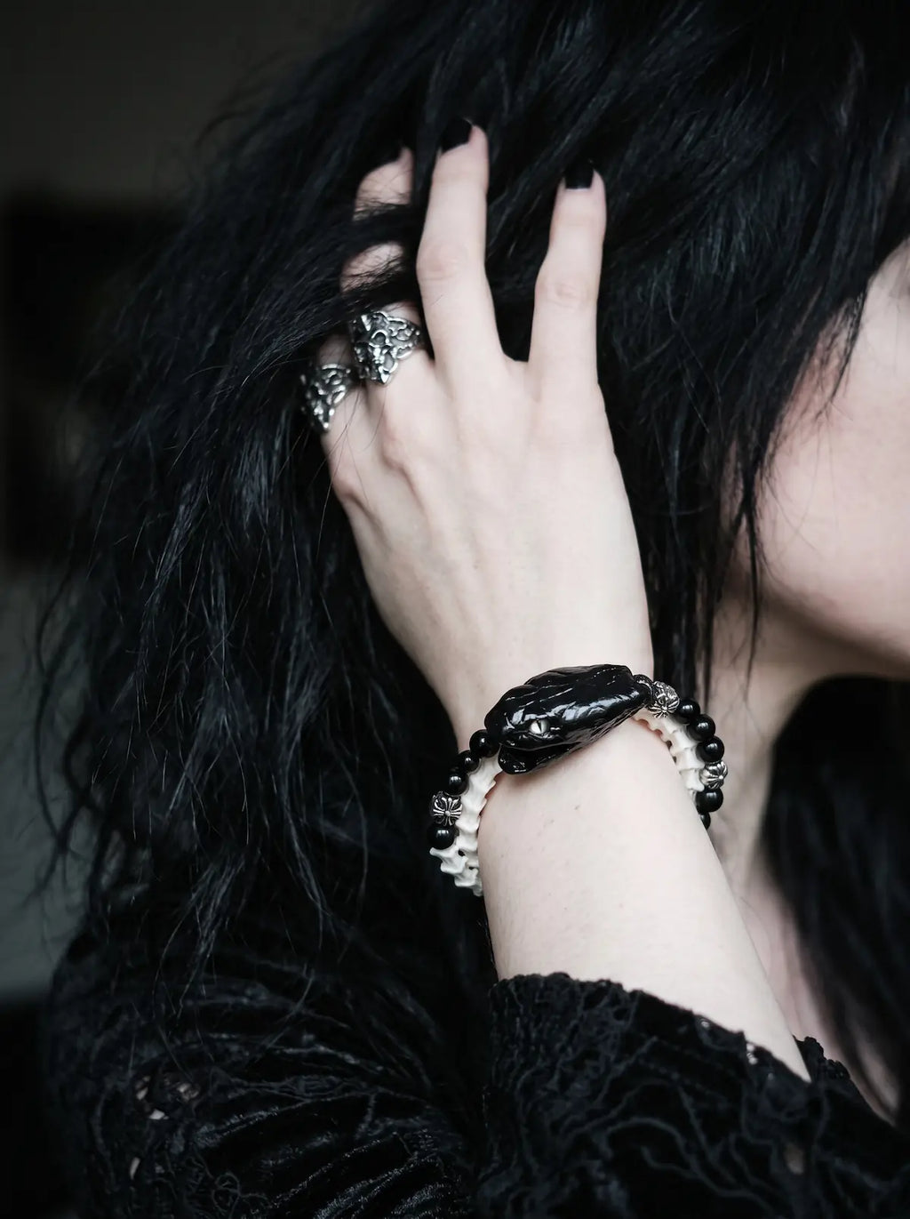 Nightreign Snake Bone Bracelet, black snake head bracelet worn on a wrist as the model touches dark hair