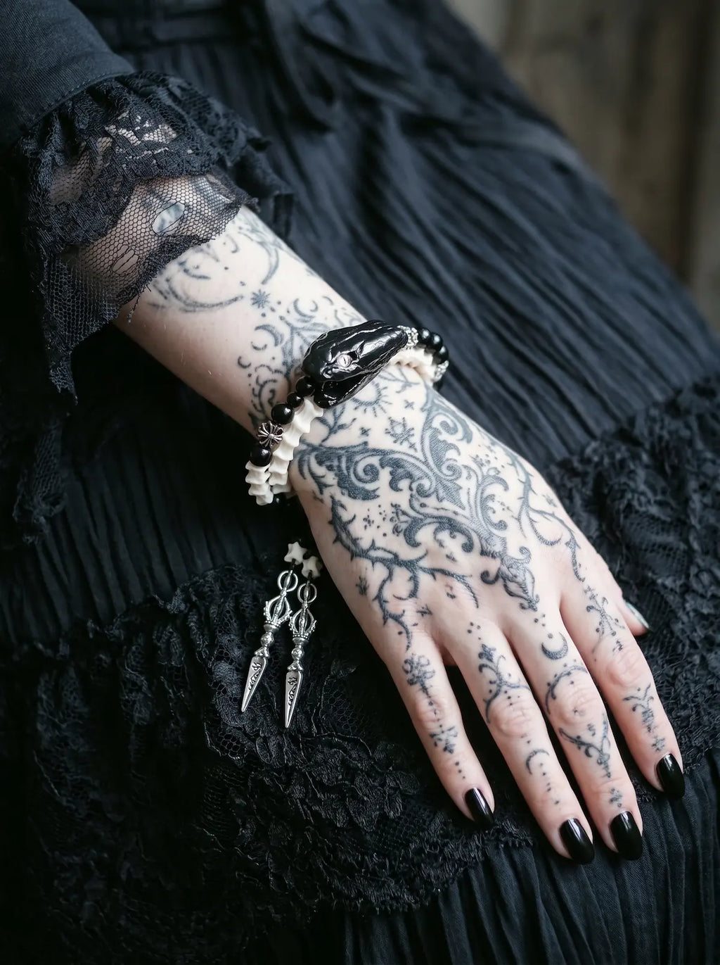 Nightreign Snake Bone Bracelet, close wrist view of preserved dark snake head and white vertebrae with pendants