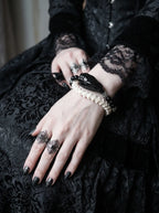 Nightreign Snake Bone Bracelet, wrist detail of pale vertebrae bracelet with dark head and hanging metal dagger