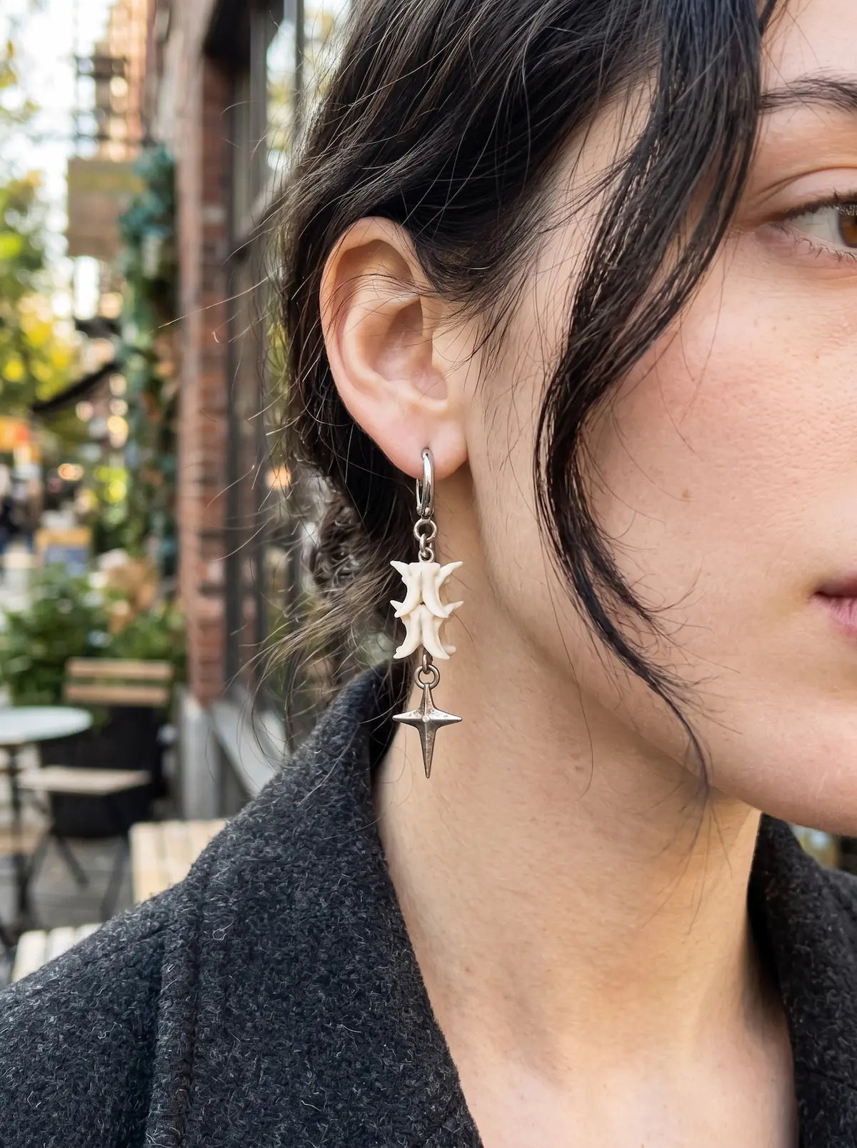 Close-up of a Nightstar snake bone earring showing its silver-tone four-point star drop