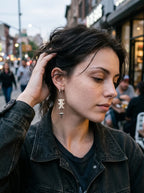 Nightstar snake bone earring worn outdoors with a hand lifting the hair away from the ear