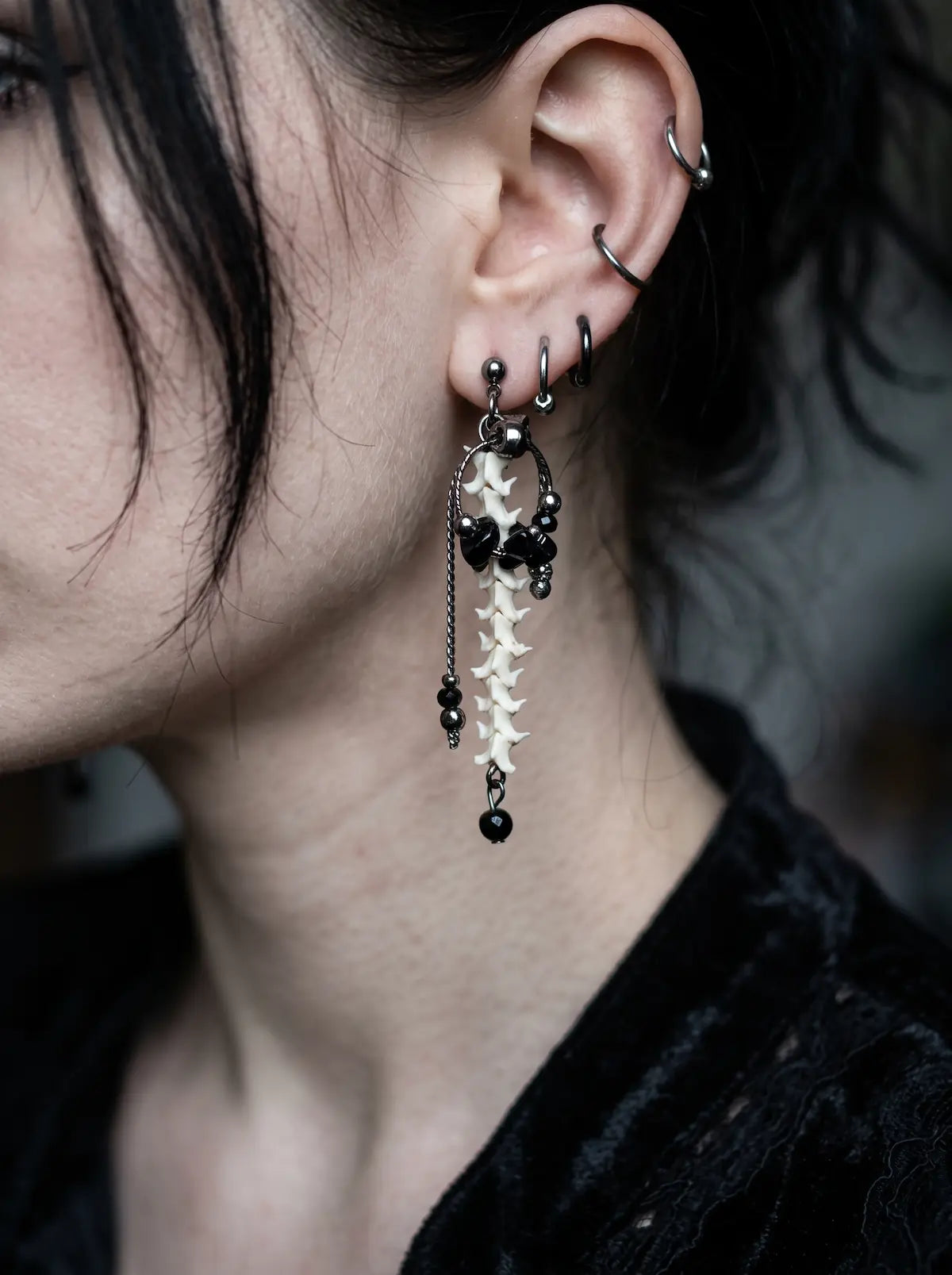 Nocturne Arc Snake Bone Earrings, slender bone drop earring with silver chains and black beads shown in side profile