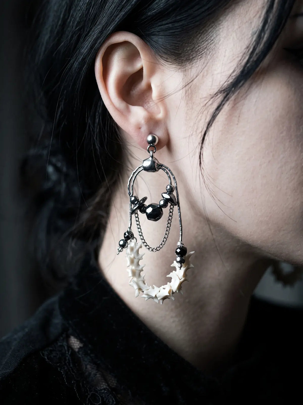 Nocturne Arc Snake Bone Earrings, curved bone hoop earring shown at the ear with black bead and metal accents