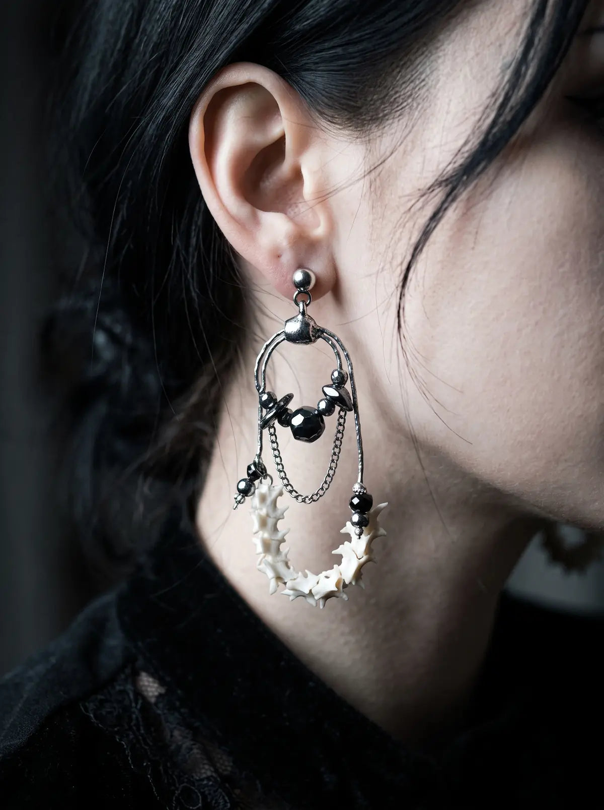 Nocturne Arc Snake Bone Earrings, curved bone hoop earring shown at the ear with black bead and metal accents