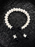 Noir Spine snake bone bracelet with glossy black beads, a black sliding knot and bone-tipped cords on patterned fabric