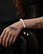 Noir Spine snake bone bracelet on a hand resting over the carved wooden arm of a dark chair