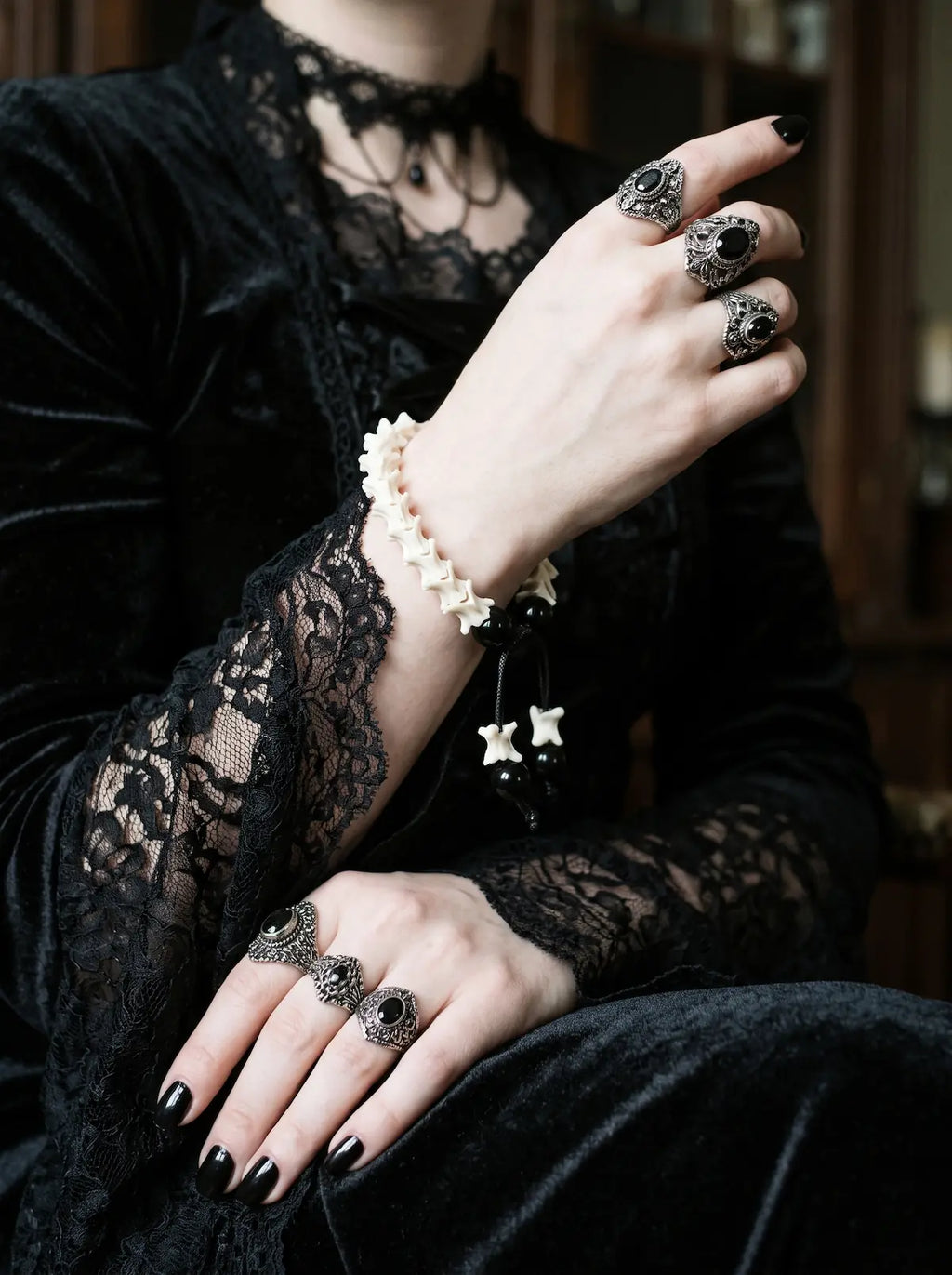 Noir Spine snake bone bracelet worn above a black lace cuff with a raised ringed hand
