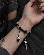 Palm-up view of the Obsidian Fang snake bone bracelet showing its braided knot and two hanging bone-tipped cords