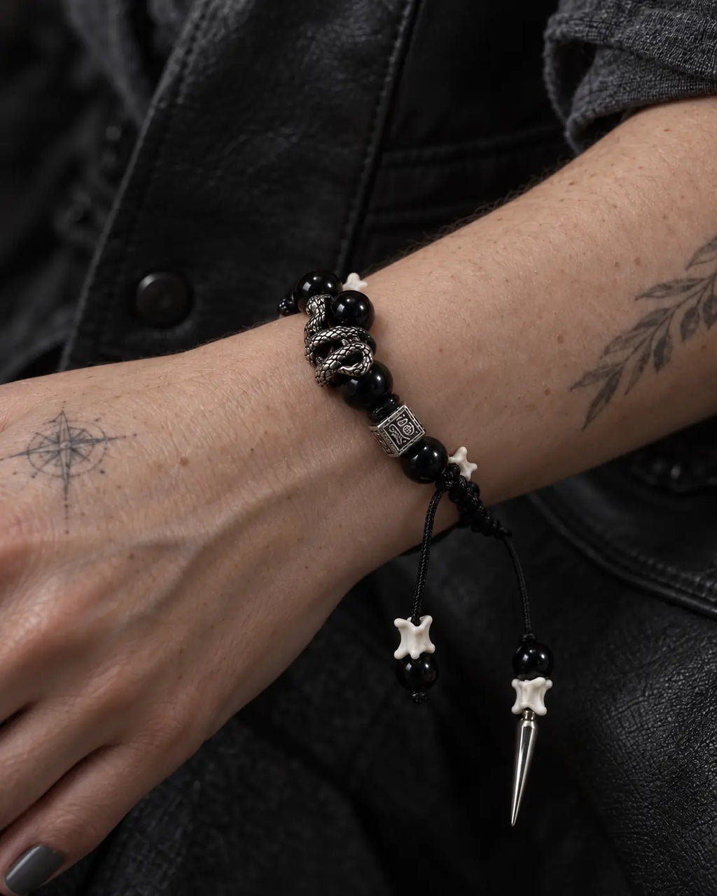Close-up of the Obsidian Fang snake bone bracelet showing the coiled serpent around a black bead on the wrist