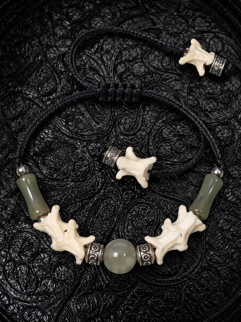 Olive Bead snake bone bracelet with green tube beads, a round green center bead and bone-tipped black cords