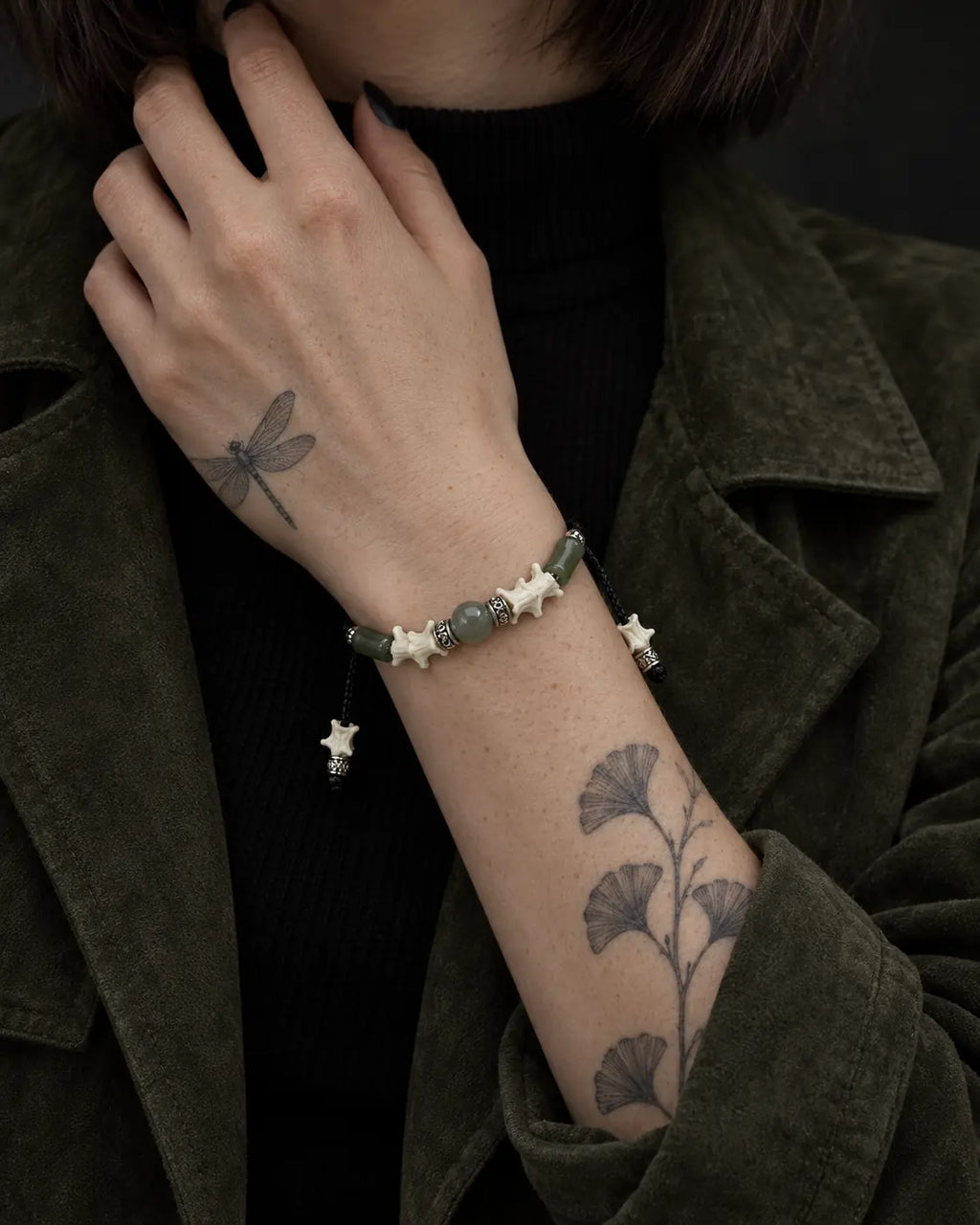 Olive Bead snake bone bracelet shown on a raised wrist with the hand at the neck