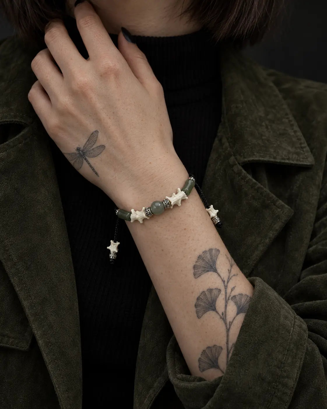 Olive Bead snake bone bracelet shown on a raised wrist with the hand at the neck