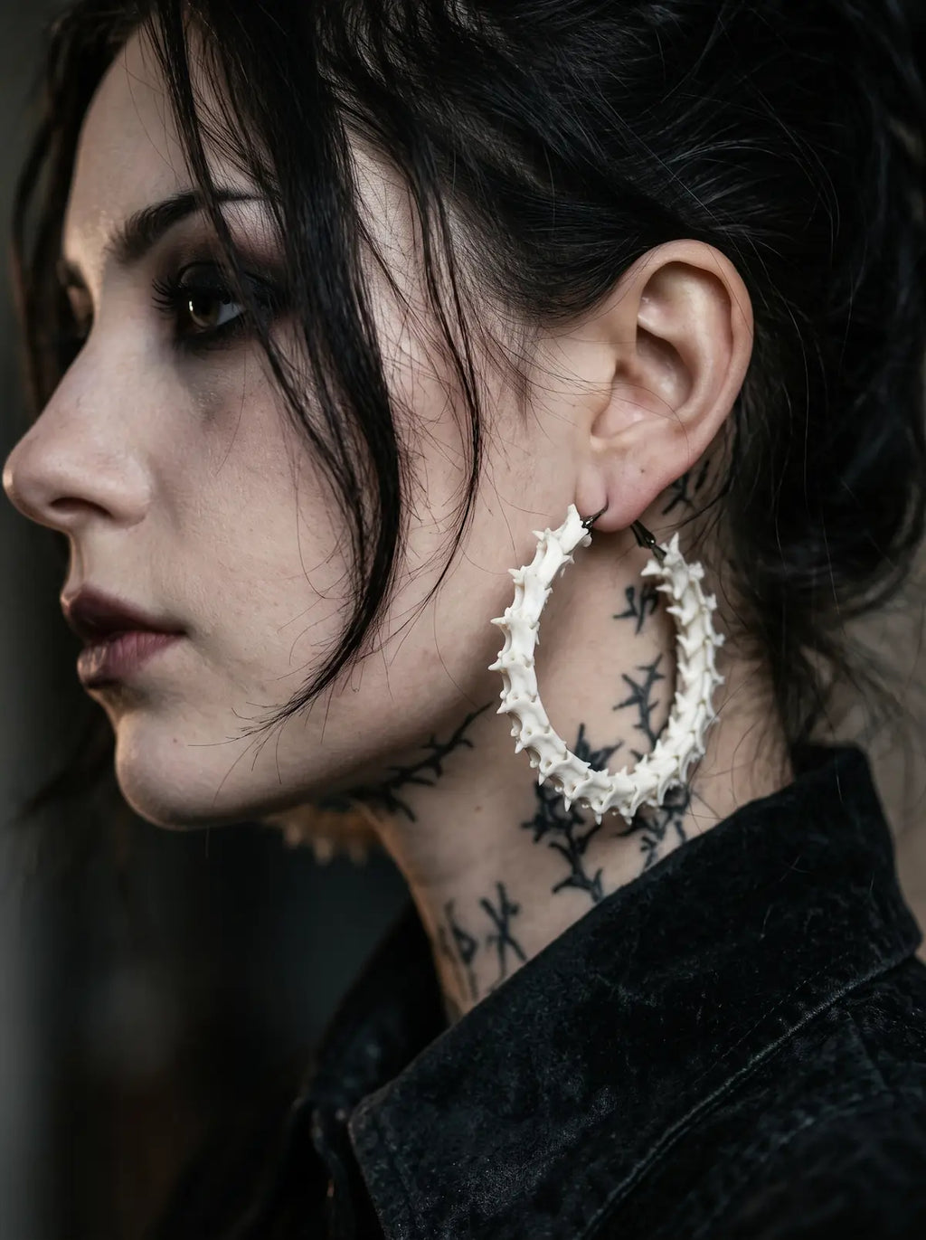 Ossuary Hoop snake bone earring shown in side profile beside a tattooed neck