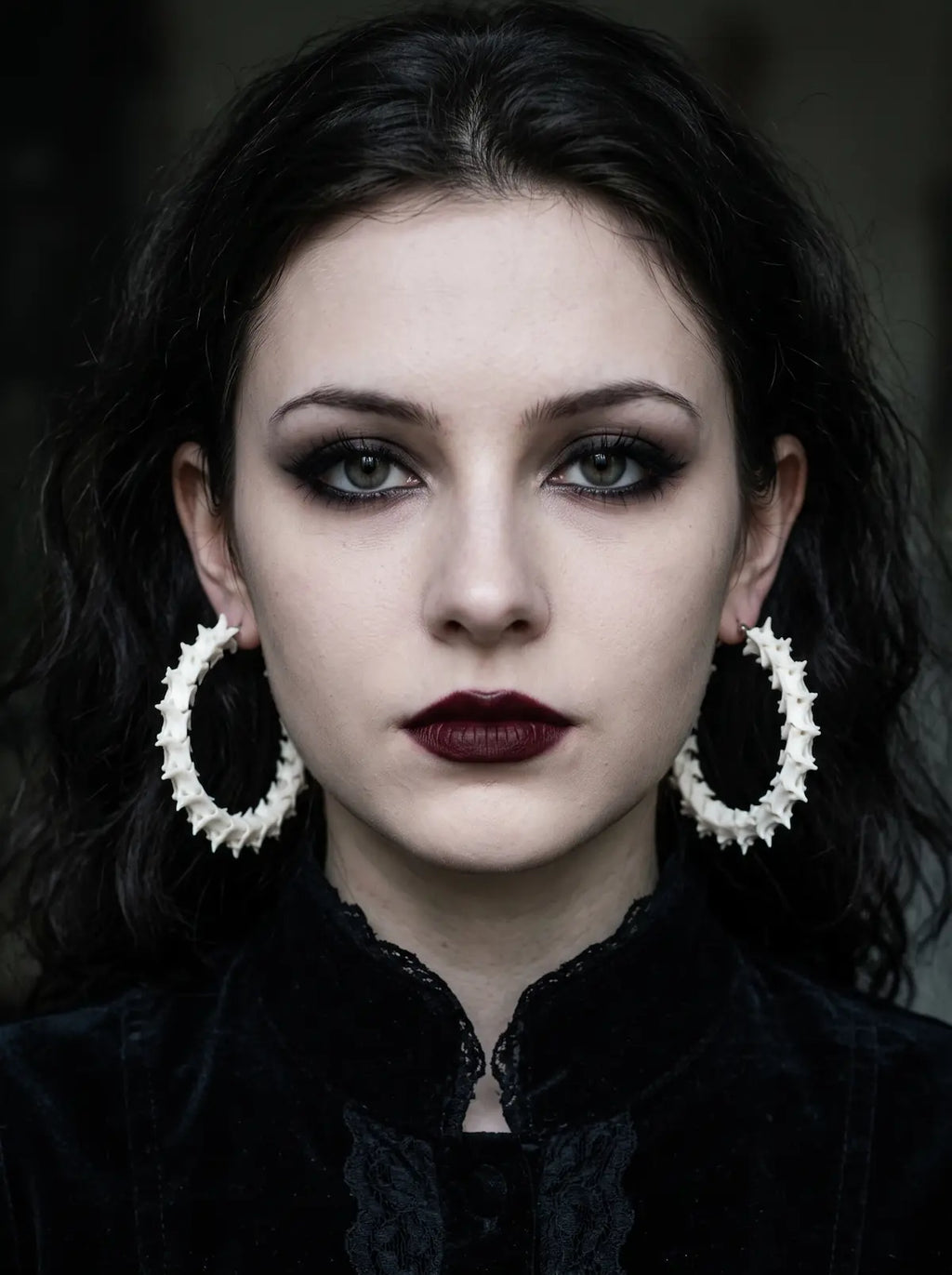 Ossuary Hoop snake bone earrings worn as a pair in a front-facing portrait against a dark background