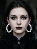 Ossuary Hoop snake bone earrings worn as a pair in a front-facing portrait against a dark background