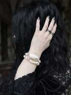 Petalshade Snake Bone Bracelet, white vertebrae bracelet with blush-pink bead accents, wrist and dark hair view