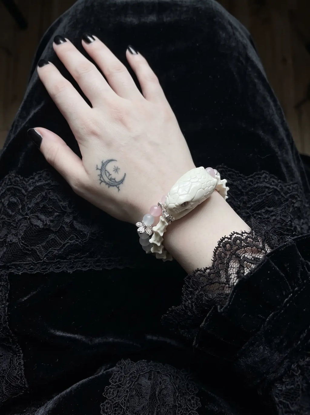 Petalshade Snake Bone Bracelet, snake head bracelet worn on a hand lifting dark hair, showing its double-row look