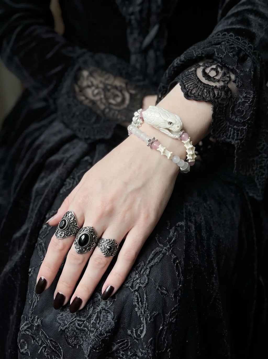 Petalshade Snake Bone Bracelet, close-up of pale snake head and light pink beaded bracelet on a resting hand