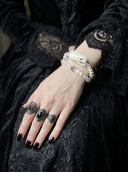 Petalshade Snake Bone Bracelet, close-up of pale snake head and light pink beaded bracelet on a resting hand