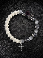 Phantom Rose snake bone bracelet with clear and milky beads, a dark rose, silver-tone wing accents and a cross charm
