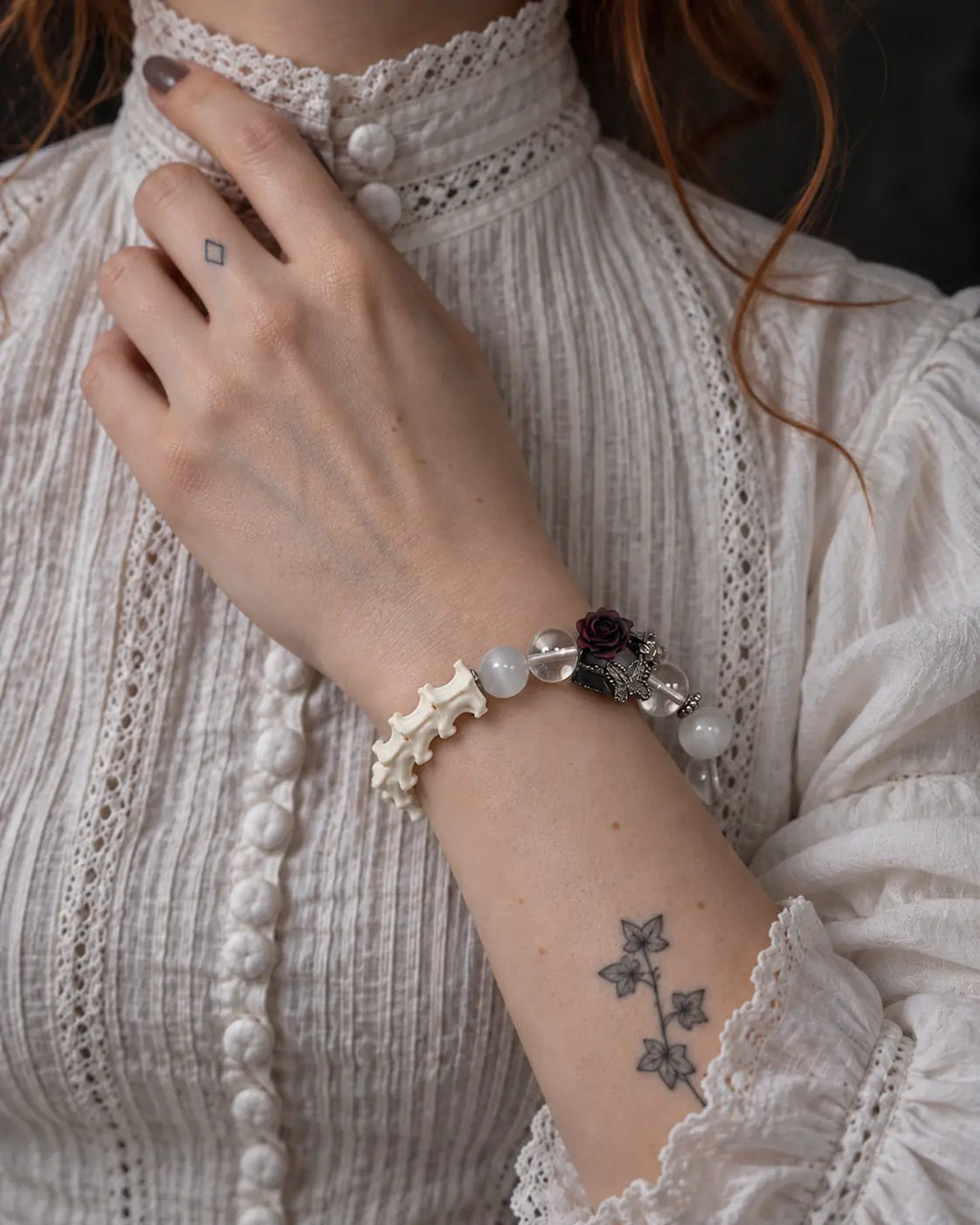 Phantom Rose snake bone bracelet worn with the hand at the collar of a white blouse