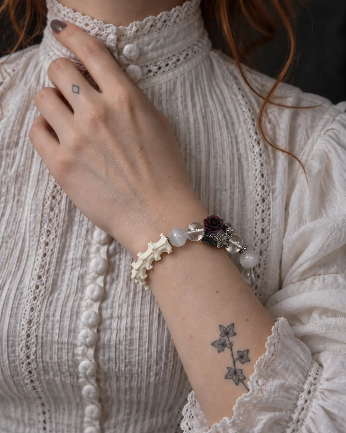 Phantom Rose snake bone bracelet worn with the hand at the collar of a white blouse