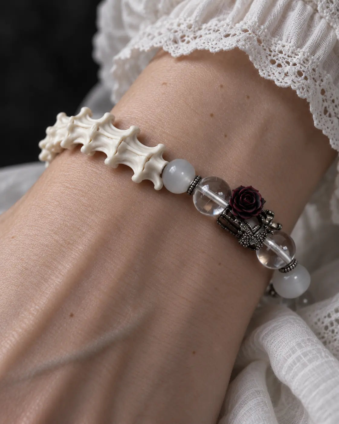 Close-up of the Phantom Rose snake bone bracelet showing white vertebrae, clear beads and a dark rose centerpiece