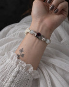 Palm-up view of the Phantom Rose snake bone bracelet showing its dark rose between clear and milky beads