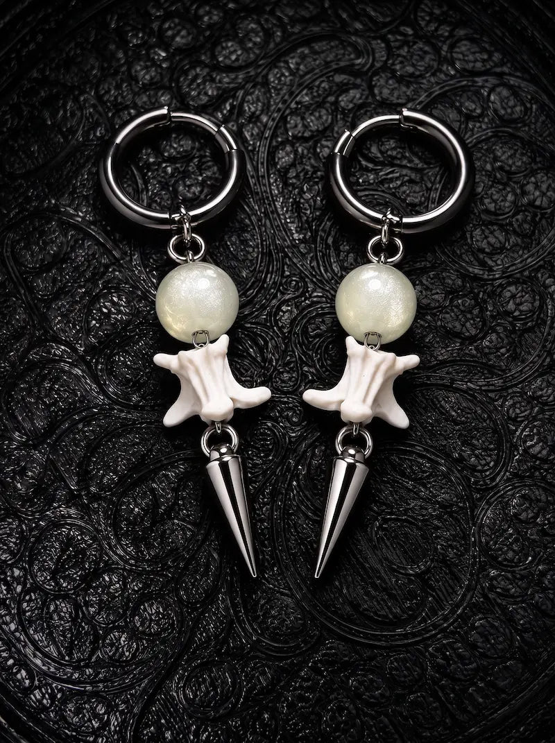 Prismatic Fang snake bone earrings with pale green beads and polished silver-tone spikes on black patterned fabric