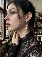 Violet-bead Prismatic Fang snake bone earring shown in close side profile with a hand at the neck