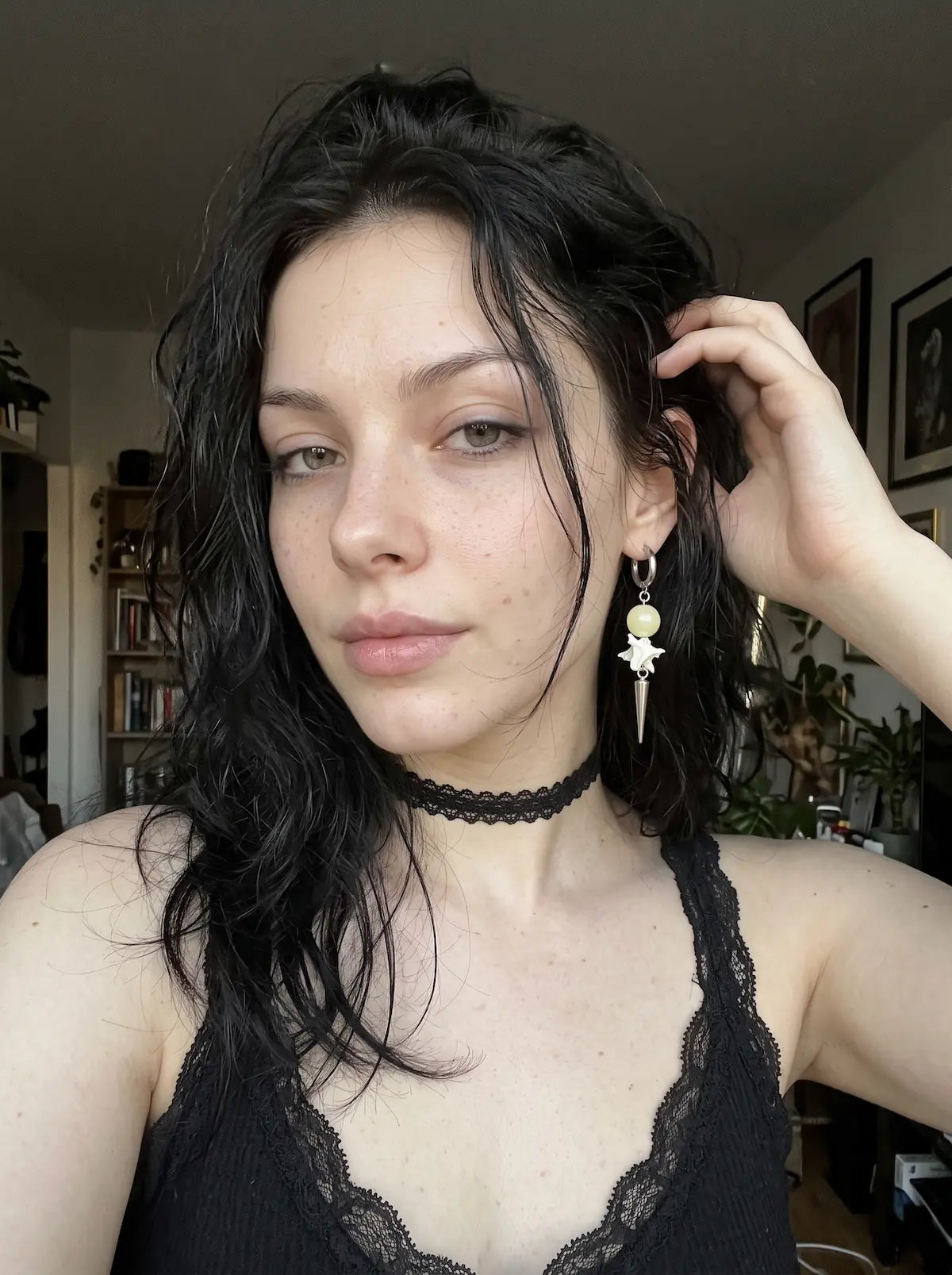 Pale green Prismatic Fang snake bone earring worn above a black lace neckline and choker