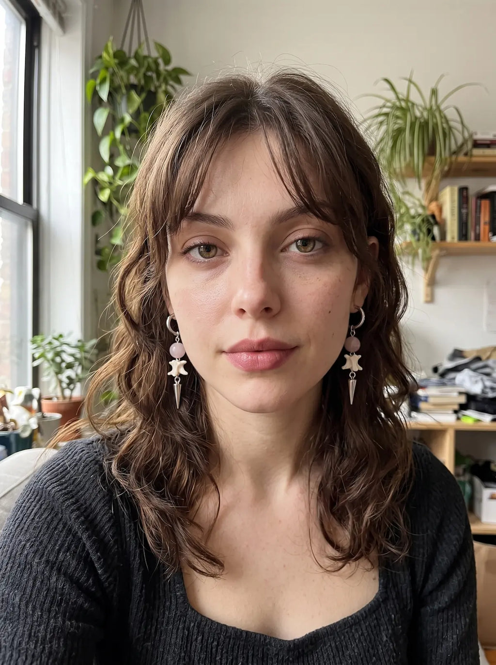 Prismatic Fang snake bone earrings with pale beads, worn as a pair in a front-facing window-lit portrait