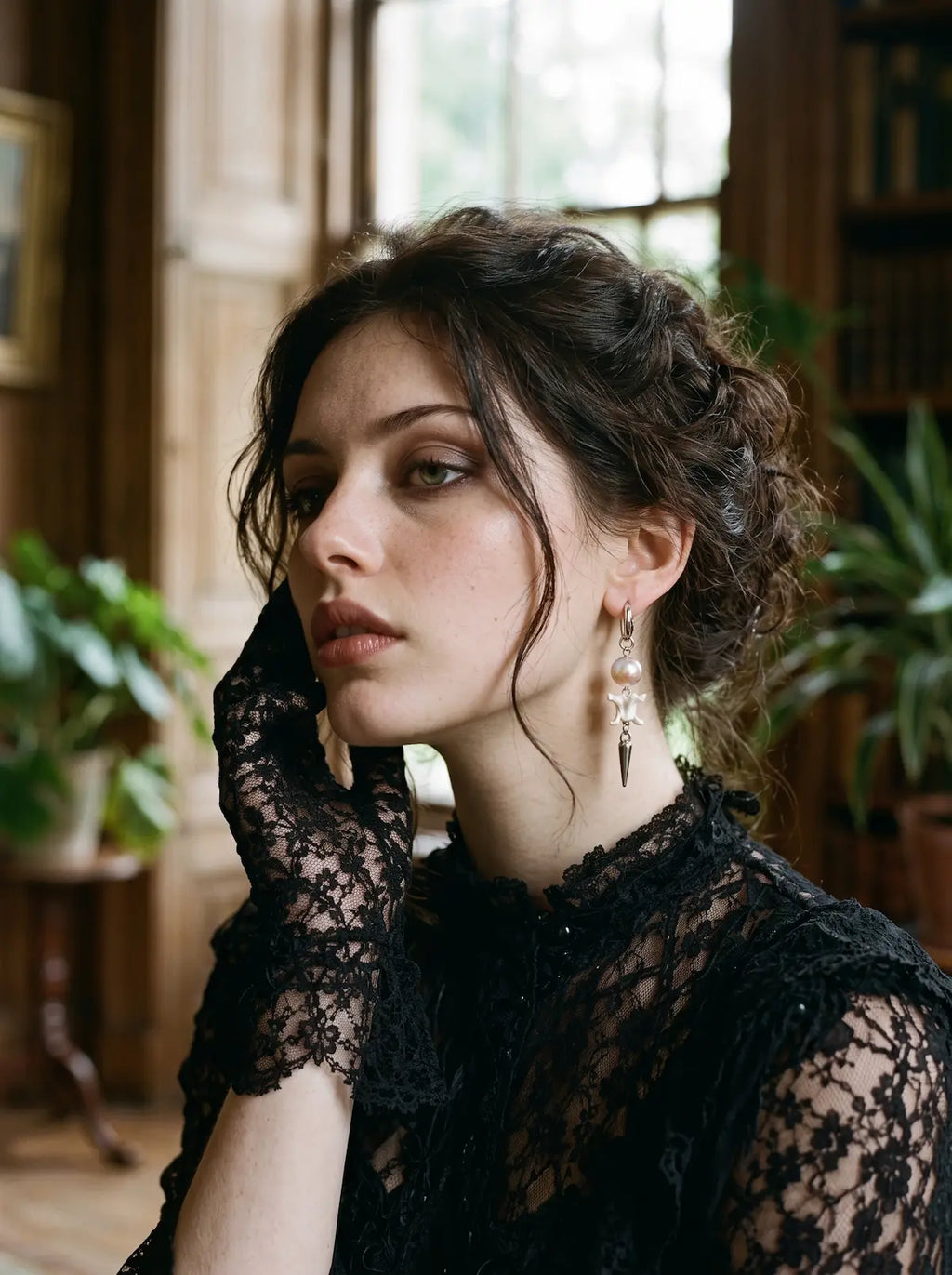 Prismatic Fang snake bone earring with a soft pink bead, worn with black lace sleeves and an updo