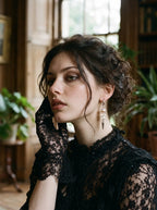 Prismatic Fang snake bone earring with a soft pink bead, worn with black lace sleeves and an updo