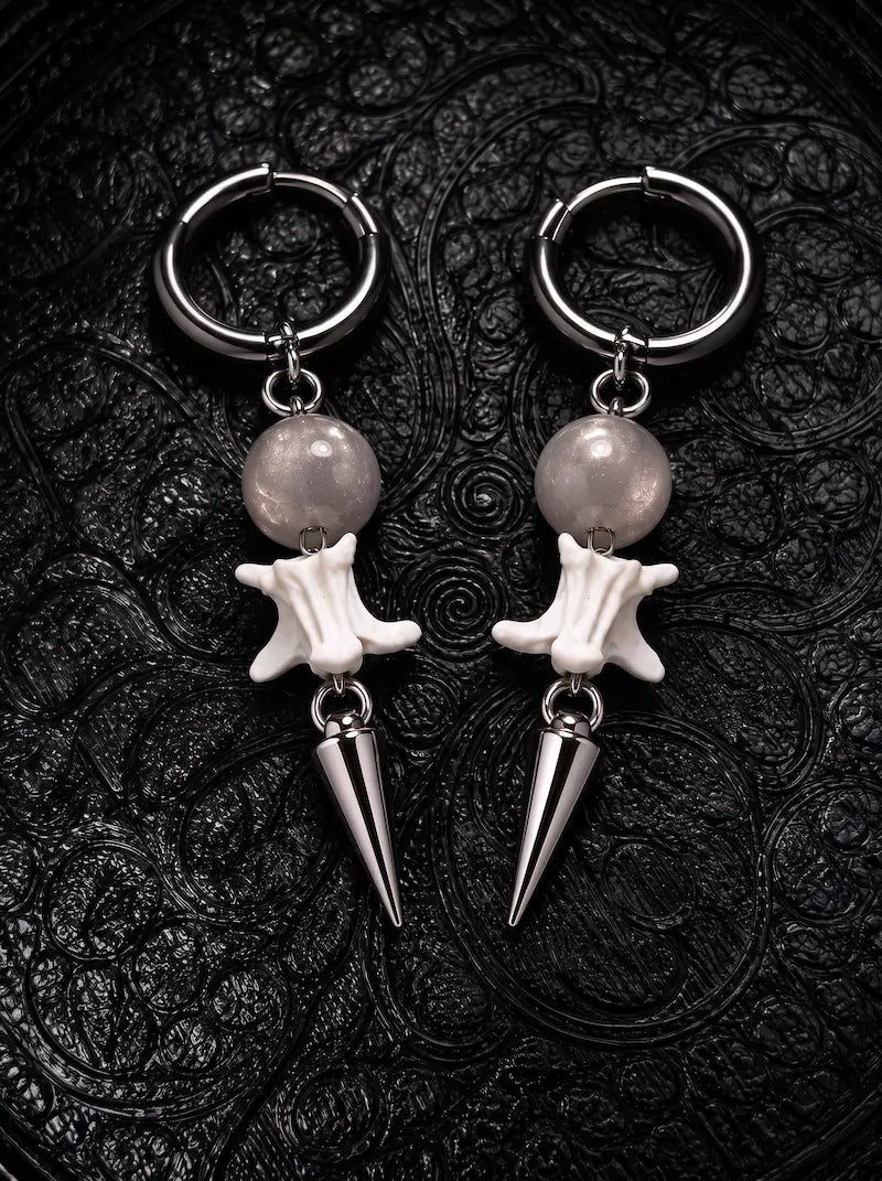 Prismatic Fang snake bone earrings with smoky gray beads and polished silver-tone spikes on black patterned fabric
