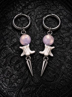 Prismatic Fang snake bone earrings with pale lavender beads and polished silver-tone spikes on black patterned fabric